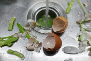 Sink full of discarded food scraps going into a garbage disposal in Culver City