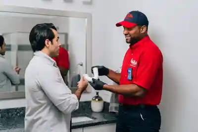 A Mr. Rooter Plumbing tech showing his customer a bathroom sink p-trap