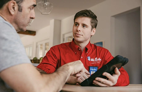 Mr. Rooter technician holding tablet while speaking with customer.