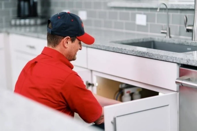 Mr. Rooter plumber working under a kitchen sink during a sink repair appointment  