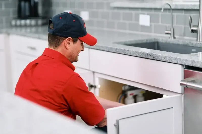 Mr. Rooter plumber completing a garbage disposal repair in a home kitchen.