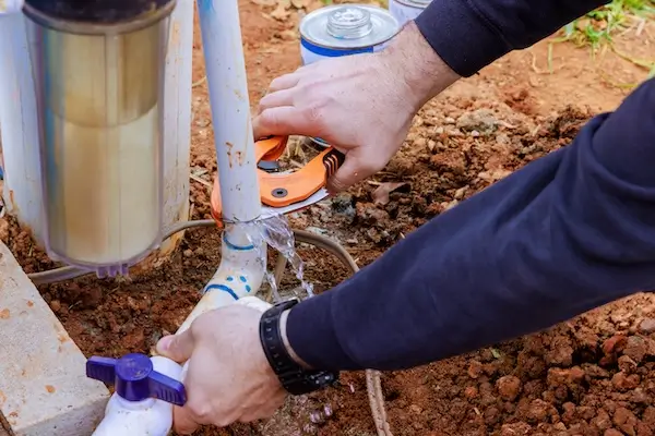 A commercial irrigation expert cutting a pipe while performing a sprinkler system repair. 