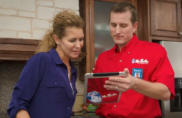 A plumber from Mr. Rooter Plumbing speaking with a homeowner about her drains and using a table to show more information about her options for plumbing service.